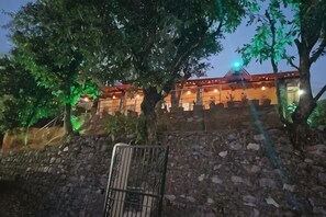 A building with a stone wall and a metal gate, surrounded by trees. - Dream Stay near Kainchi DHAM (Nainital)