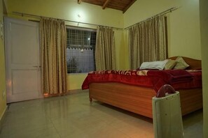 Ein Schlafzimmer mit Bett, Vorhängen, einem Fenster und einer Tür.