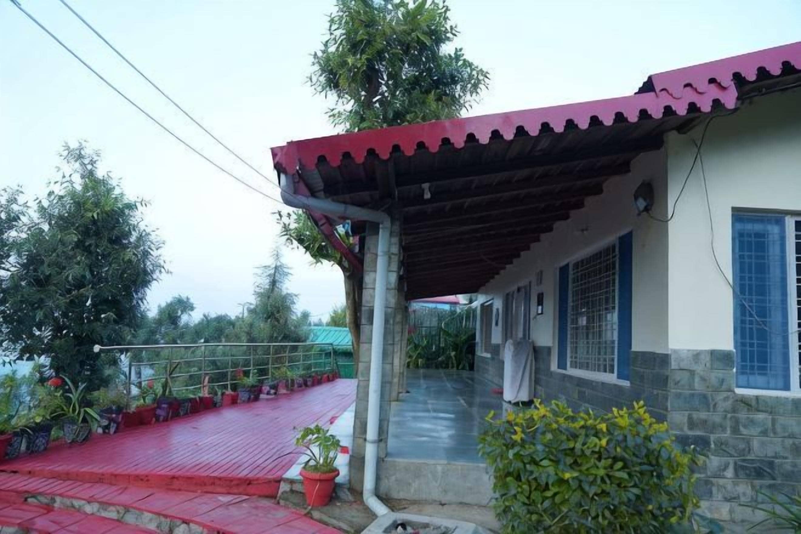 A building with a covered porch, a stone wall, and a red pathway leading to the entrance.