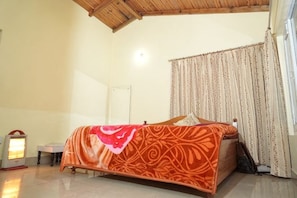 A bedroom with a bed, a bedside table, a lamp, and a curtain.