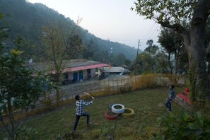 A rural outdoor setting with a fenced area, a building with a red roof, and a person playing with a ball.