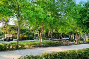 A park with trees, a paved walkway, and a bench.