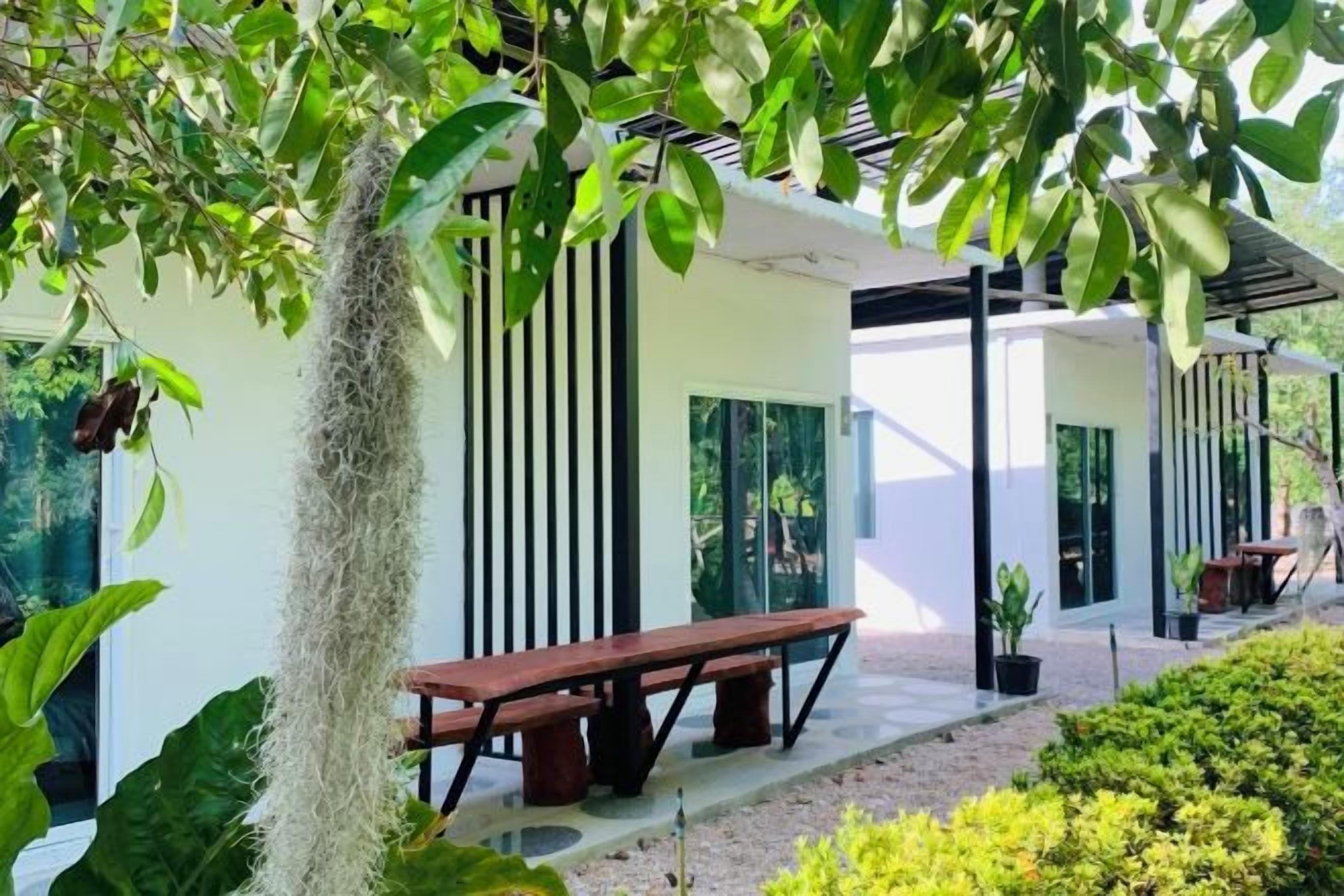 Un espace extérieur moderne, aménagé avec un banc et une table, entouré de verdure et bordé par un bâtiment aux lignes verticales.