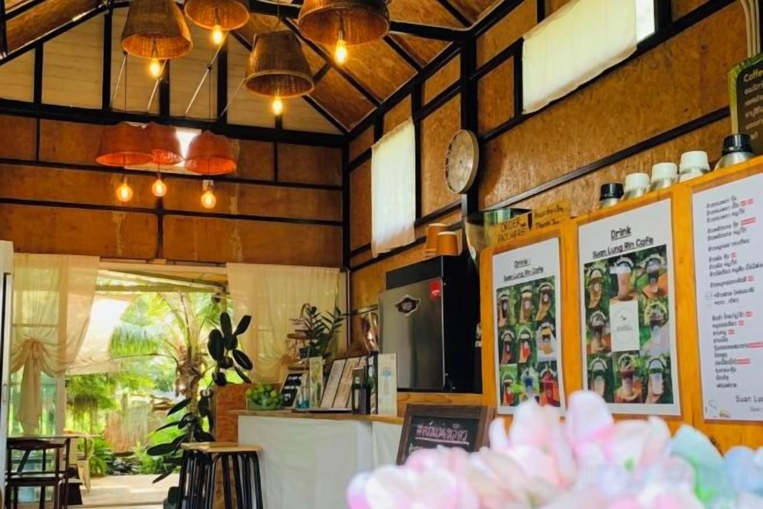 A restaurant interior with wooden beams, hanging light fixtures, and a menu board.