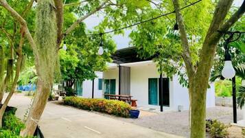 Un bâtiment moderne doté d’un espace extérieur aménagé et abrité, entouré d’arbres et de verdure.