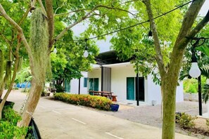 A modern building with a covered outdoor seating area, surrounded by trees and greenery. - Suan Lung Rin Resort Cha Am (Cha-am)