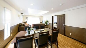 A dining area with a table set for four, a sofa, and a window with curtains. - Dynasty 24 (Sapporo)