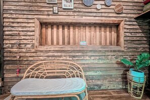 A rustic wooden wall with a window, a wicker chair, and a potted plant.