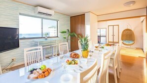 Un coin repas avec une table mise pour le repas, des chaises, un téléviseur et une vue sur l’océan.