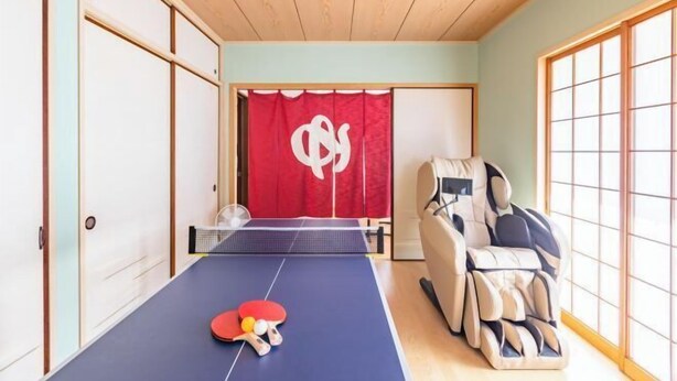 Une pièce équipée d’une table de ping-pong, d’un fauteuil de massage et de portes coulissantes de style japonais traditionnel.