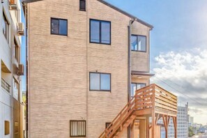 A multi-story building with a brick facade, a wooden staircase, and a visible window. - LONG VACATION (Shirahama)