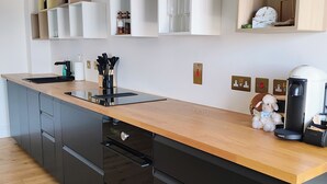 A modern kitchen with a wooden countertop, built-in cabinets, and a coffee machine. - Lavish Collections  (Great Yarmouth)