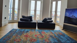 A room with a large window, a flat-screen TV, and a patterned rug. - Lavish Collections  (Great Yarmouth)
