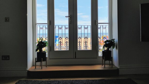 A double door entrance with a view of the beach and a balcony with metal railings. - Lavish Collections  (Great Yarmouth)