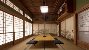 Una habitación japonesa tradicional con suelo de tatami, una mesa baja, puertas correderas y un farol colgante.