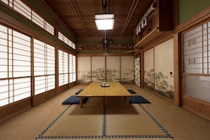 Una habitación japonesa tradicional con suelo de tatami, una mesa baja, puertas correderas y un farol colgante.