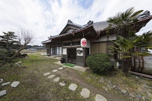 A traditional Japanese building with a tiled roof, a signboard, and a stone pathway leading to the entrance. - Tsubakihausu (Kozaki)