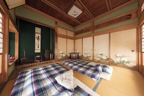 Una tradizionale stanza giapponese con pavimenti in tatami, due letti di tatami, un paravento shoji e un rotolo appeso.