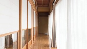 Un pasillo con suelo de madera y ventanas amplias a un lado.