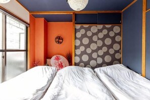 A room with a bed, a wall with a polka dot pattern, and a window. - Aladdin House (Tokyo)
