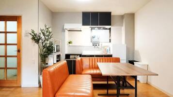 A compact living space with a kitchenette, a dining area with a table and benches, and a wooden floor.