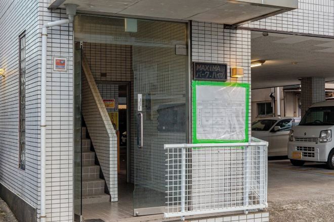 A building entrance with a glass door, a staircase, and a sign indicating a maximum height of 2.1 meters.