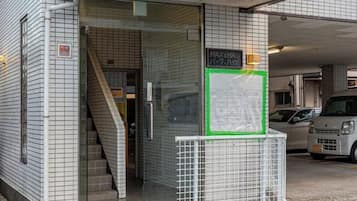 A building entrance with a glass door, a staircase, and a sign indicating a maximum height of 2.1 meters.