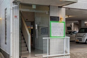 A building entrance with a glass door, a staircase, and a sign indicating a maximum height of 2.1 meters. - Aladdin House (Tokyo)