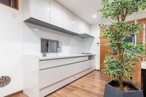 Een moderne keuken met witte kasten, een ingebouwde oven en een houten vloer.