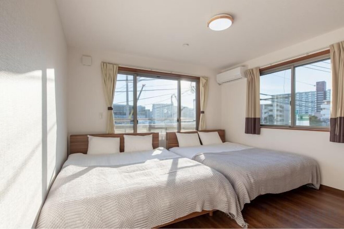 A hotel room with two beds, large windows, and a view of the city.