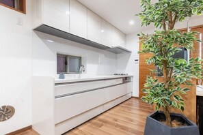 Une cuisine moderne avec des armoires blanches, un four encastré et une plante en pot.