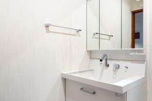 A bathroom with a white sink, a mirror, and a towel rack. - Residential Voyan Minamisunacho (Tokyo)