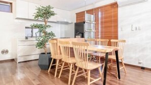 A modern kitchen with a dining table and chairs, a potted plant, and a built-in oven. - Residential Voyan Minamisunacho (Tokyo)