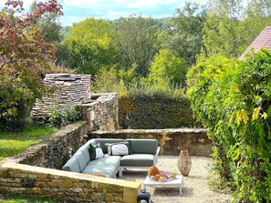 A stone structure with a green sofa and a table with fruit and cups.