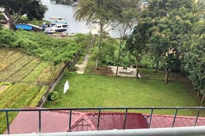 A view of a river with boats, a grassy area, and trees. - Matraville Home Stay Lake Toba (Tuktuk Siadong)