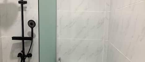 A bathroom with a shower, toilet, and a wall with a marble pattern.