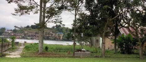 A grassy area with trees and a view of a river and buildings in the distance.