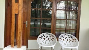 Puerta de madera con un panel de vidrio y dos sillas de plástico blancas al frente.