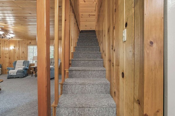 A wooden interior with a carpeted staircase leading to a second floor. - Dogwood Star – Star Location + Cozy Vibes (Shaver Lake)