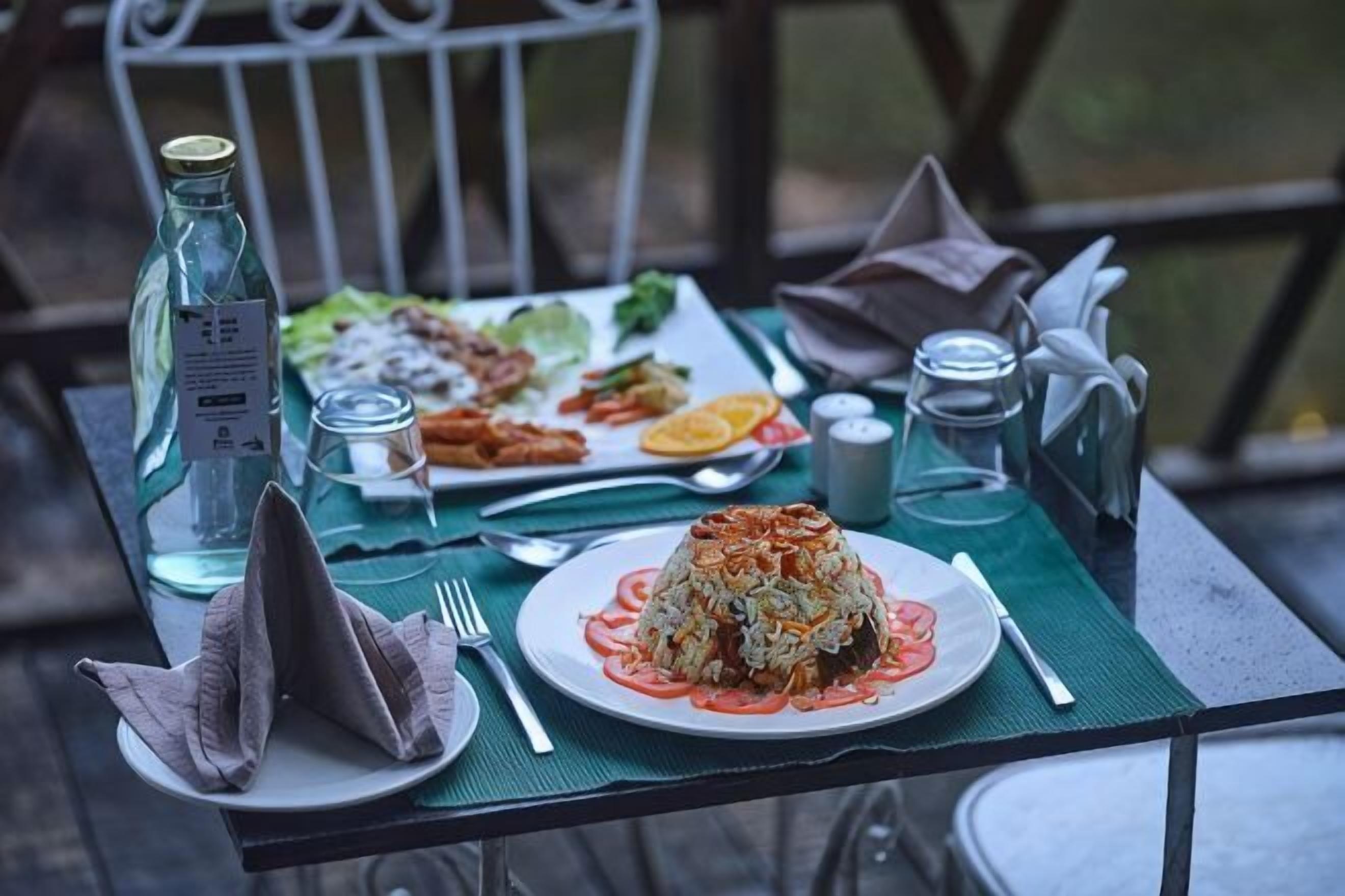 A table set with plates of food, a bottle, and glasses.