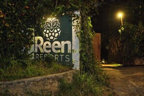 A sign for 'Reen Resorts' with a logo, surrounded by greenery and a pathway leading to the entrance. - Reen Resorts Aanavilasam Plantation Thekkady (Thekkady)
