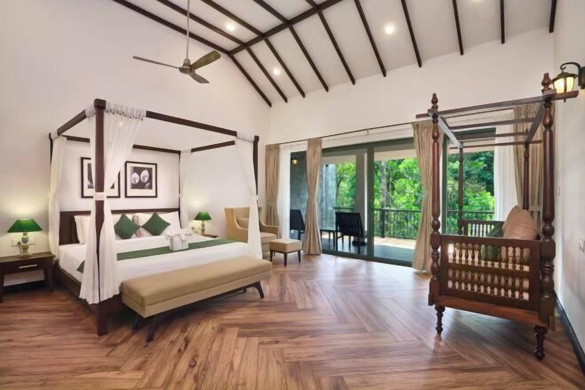 Une chambre à coucher avec un lit à baldaquin, un banc, un ventilateur de plafond et une vue sur l’extérieur.