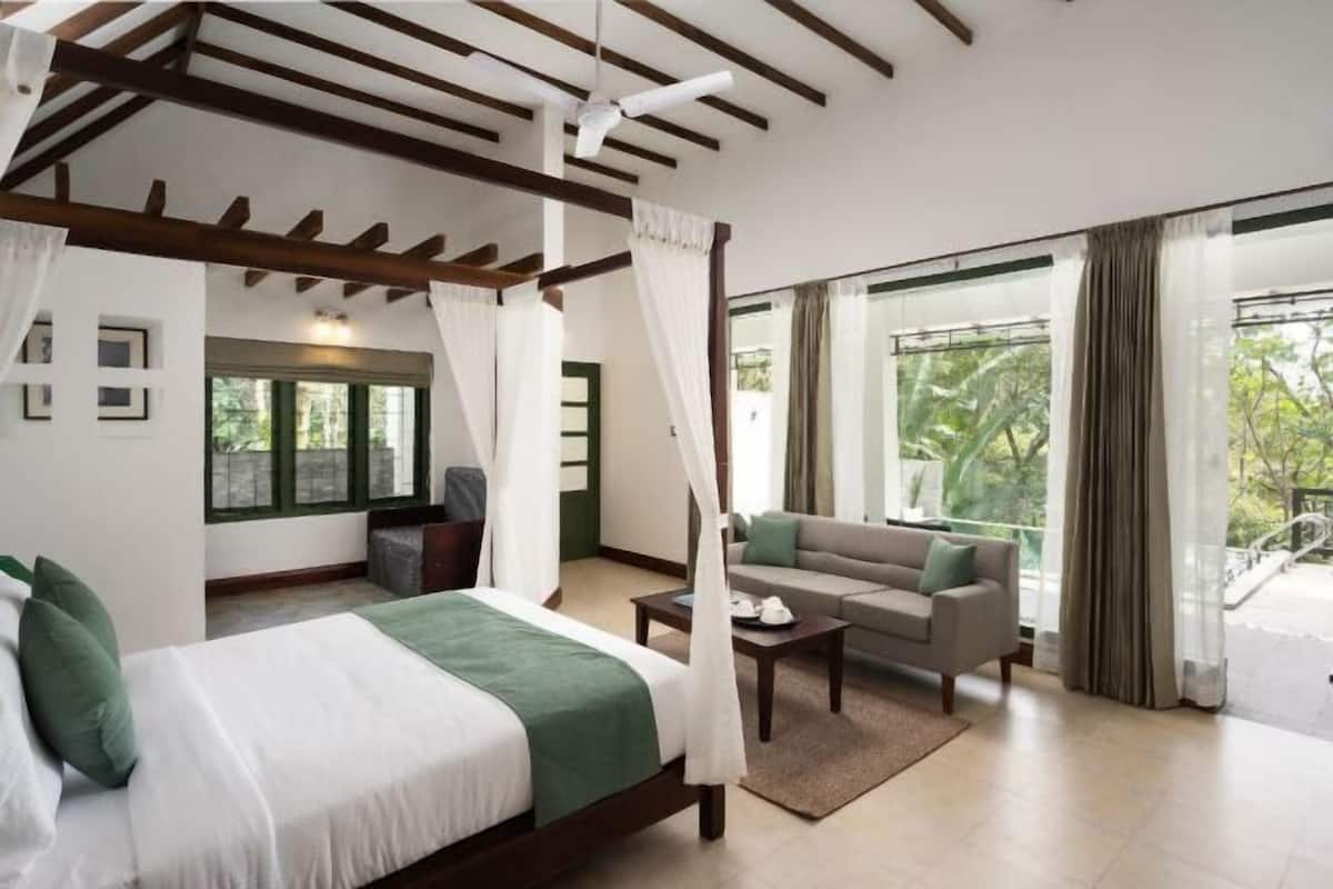 Une chambre à coucher avec un lit à baldaquin, un canapé, une petite table et un balcon agrémenté de rideaux.