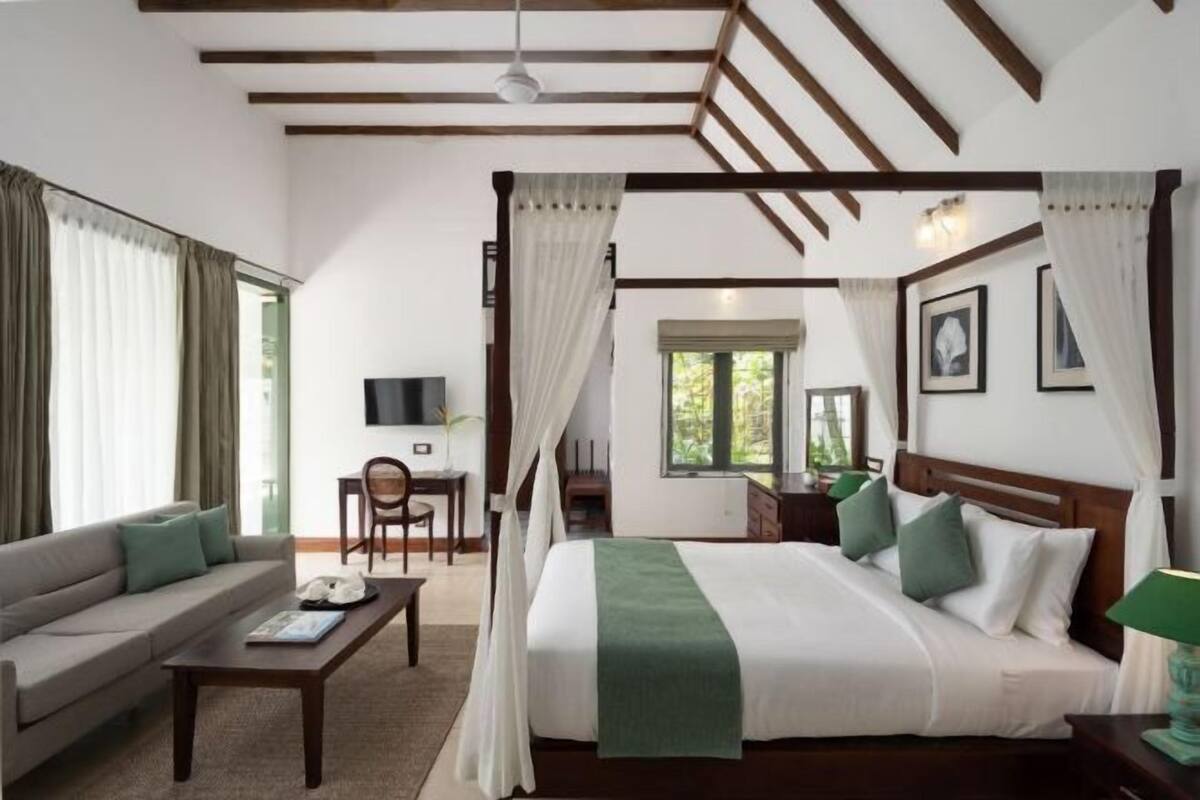 Une chambre à coucher avec un lit à baldaquin, un canapé, un bureau et une télévision.