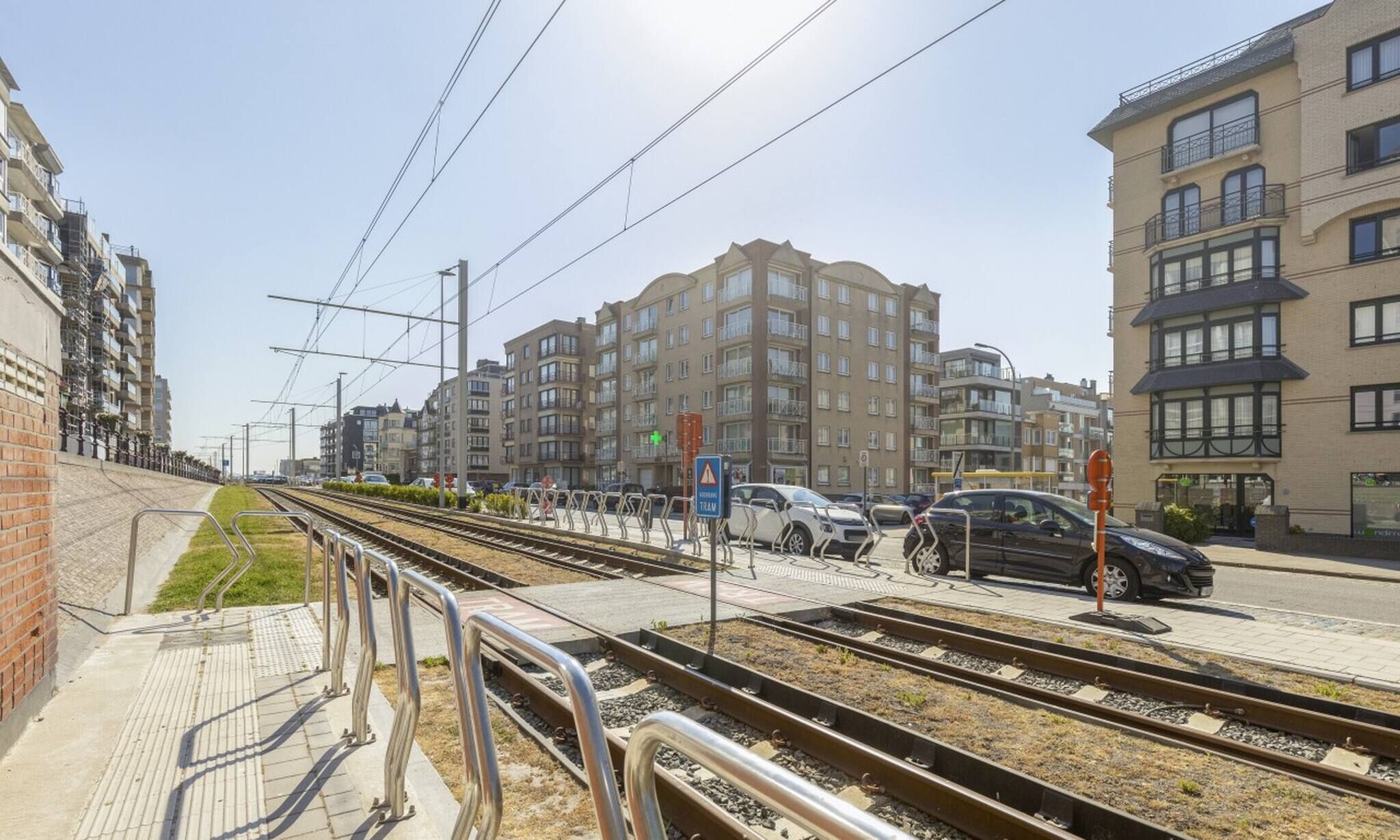 A train station platform with multiple tracks and a pedestrian walkway.