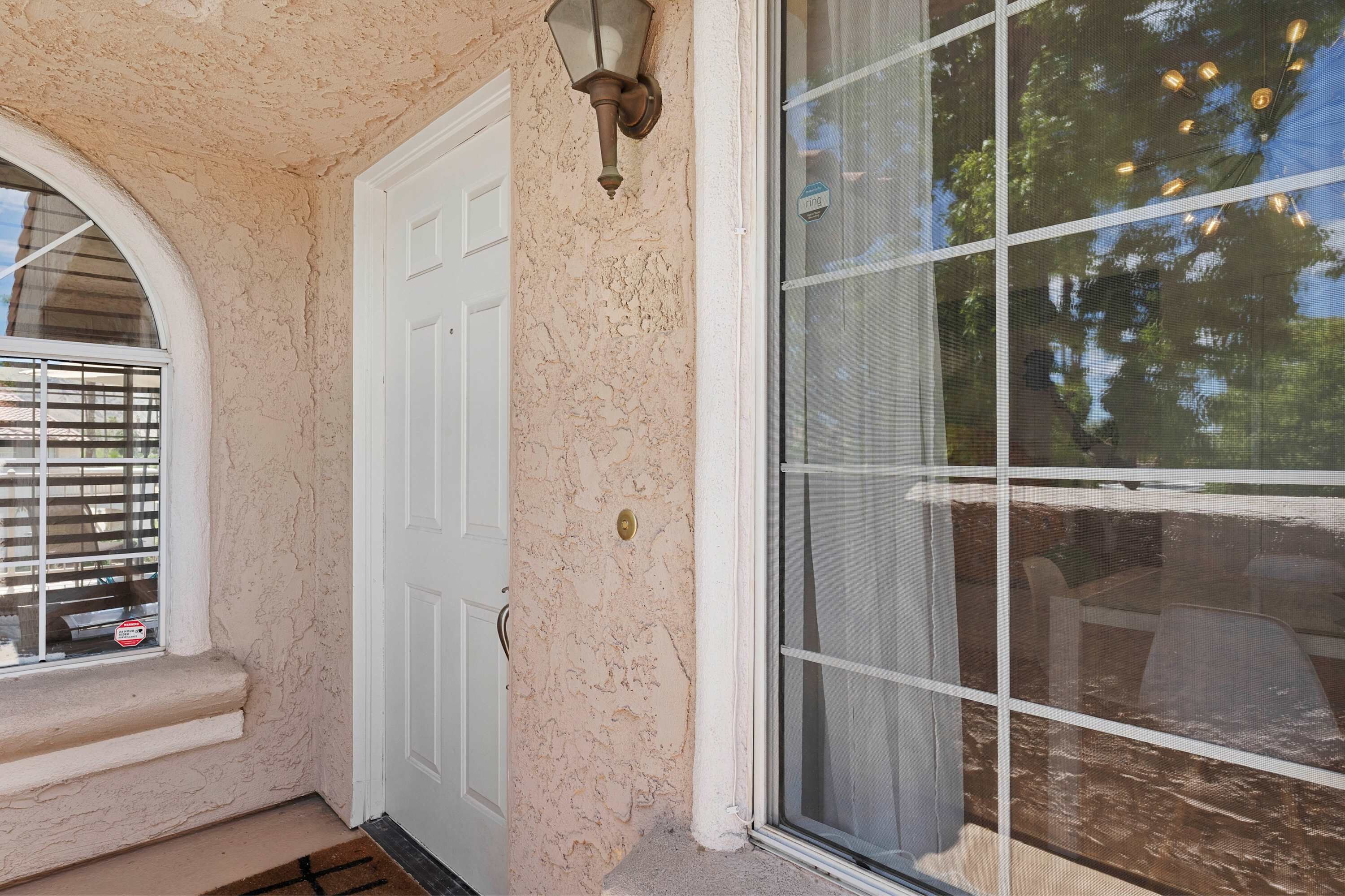 A door with a textured wall, a window with blinds, and a doorbell.