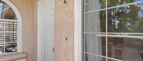 A door with a textured wall, a window with blinds, and a doorbell.