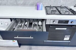 A kitchen with a built-in dishwasher, a gas stove, and a drawer with utensils. - Modern Garden Retreat - Near Wfj, 3Br Ensuite & Parking (Watford)