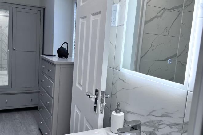 Ein Badezimmer mit Marmorwand, Papierhalter und einem grauen Schrank.