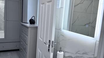 Ein Badezimmer mit Marmorwand, Papierhalter und einem grauen Schrank.